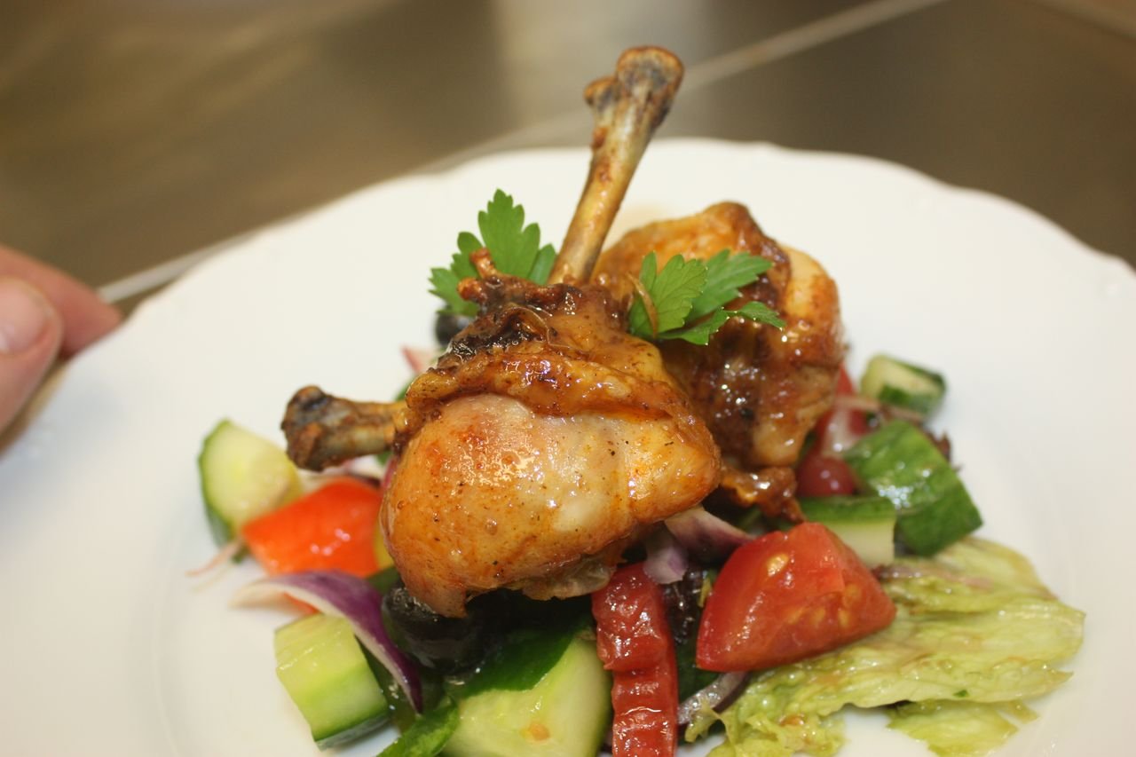 HOME Close-up of a delicious chicken drumstick meal, garnished with fresh veggies.