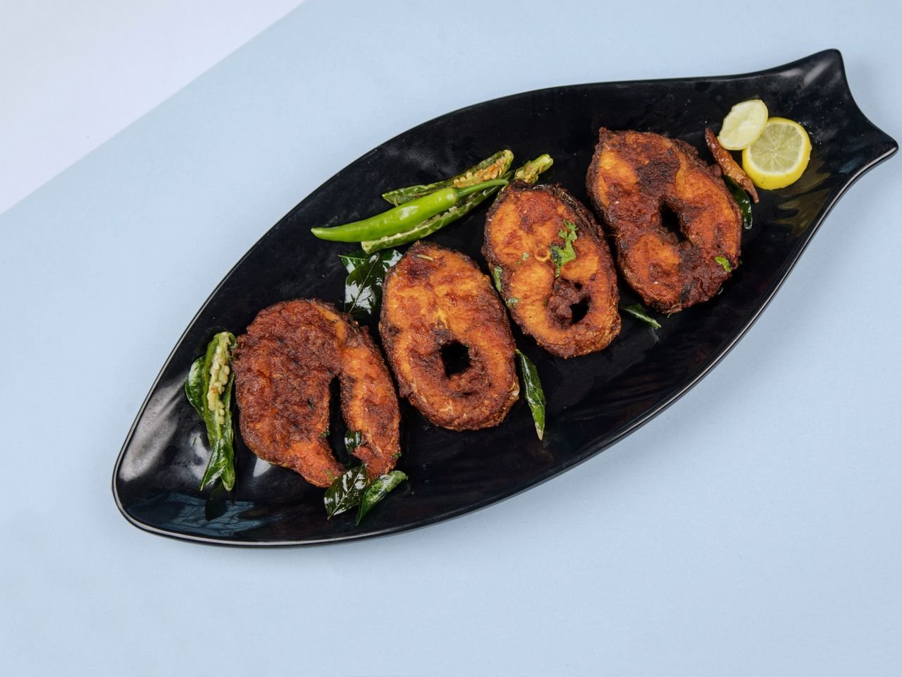HOME Delicious crispy fried fish served with lemon and chili on a stylish black plate.