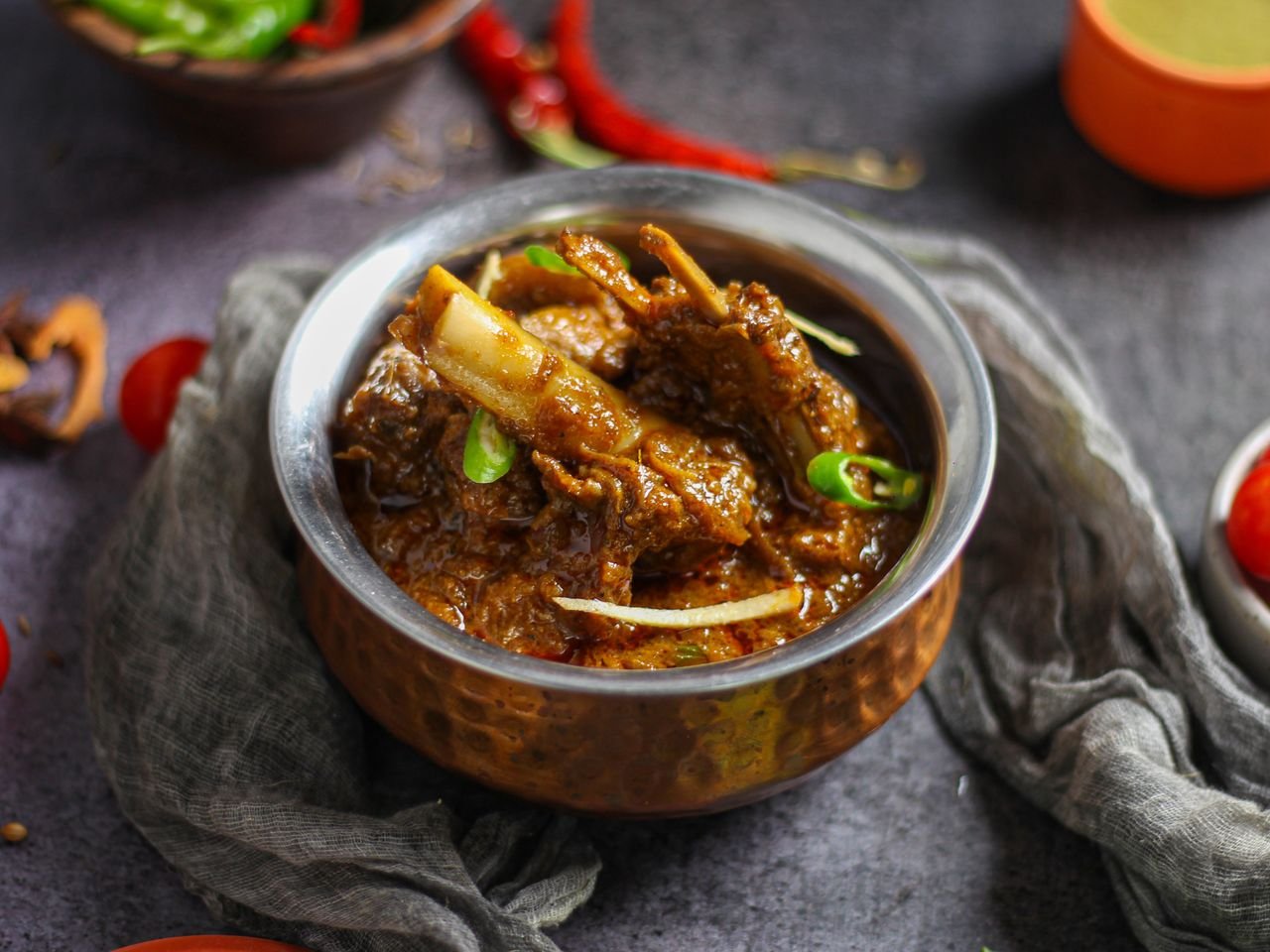 HOME Close-up of a spicy mutton curry served in a traditional copper bowl, showcasing rich Indian flavors.